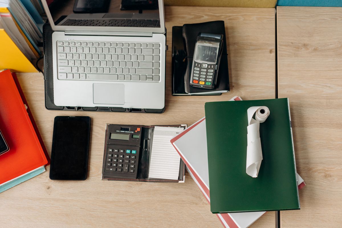 Desk with calculator, laptop and paperwork